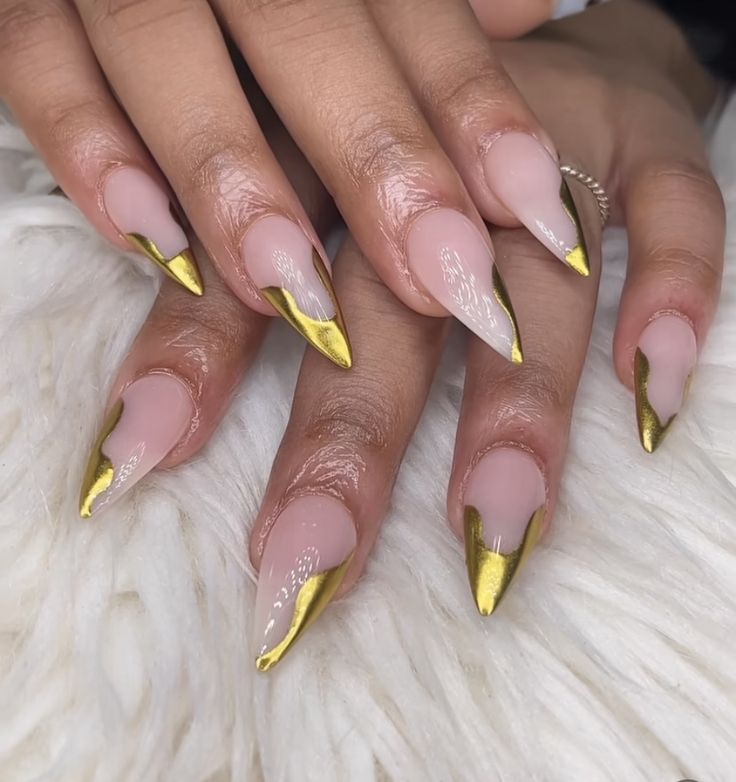 Sophisticated Stiletto Nails: Subtle Nude Base with Glamorous Gold Accents.