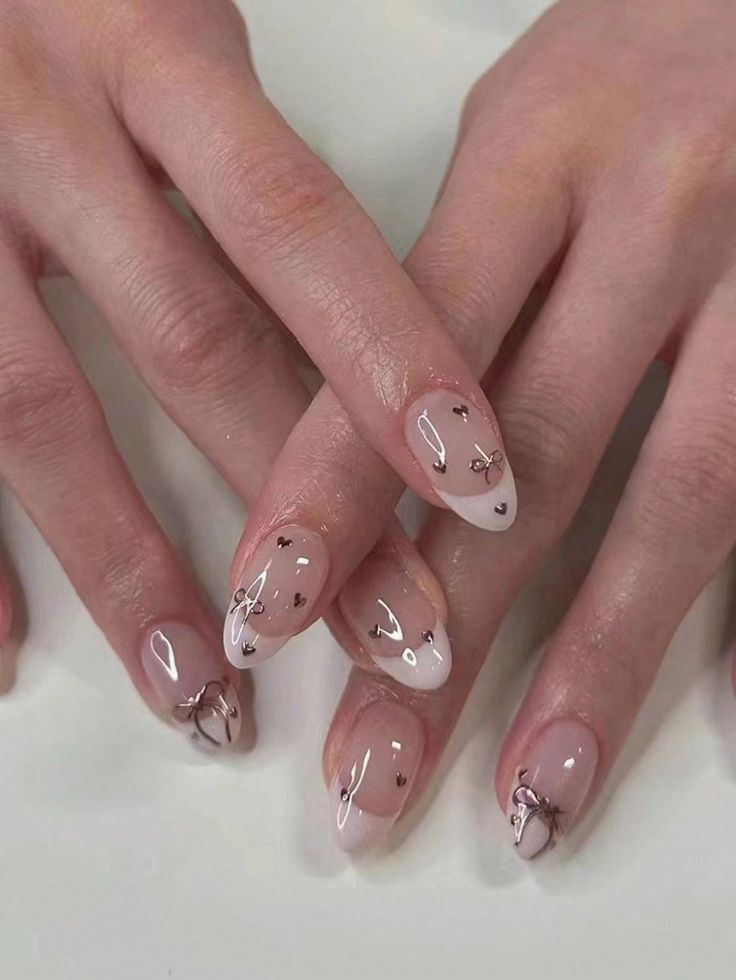 Chic Nude French Tip Nail Design with Delicate Bows and Metallic Accents.