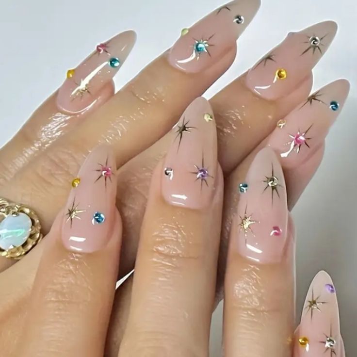 Chic Nude Nail Design with Starburst Accents and Multicolored Rhinestones.