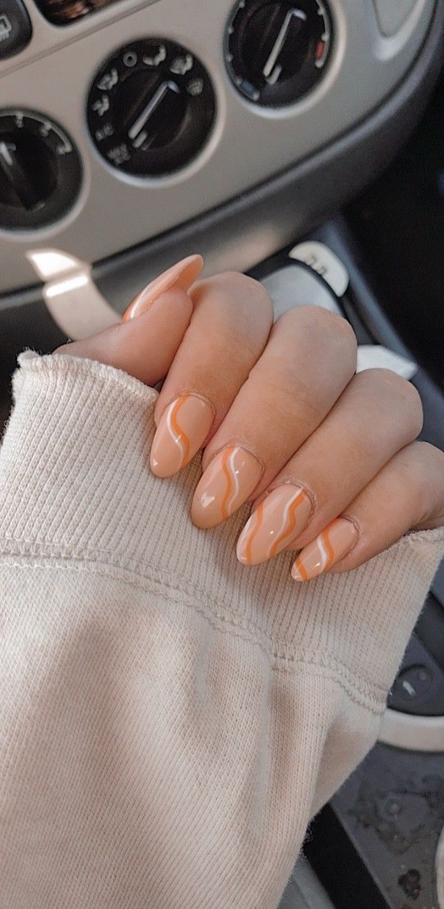 Trendy Almond-Shaped Nails with Warm Nude Base and Wavy Orange Accents.