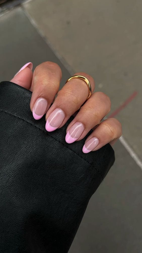 Chic Modern French Manicure with Nude Base and Pink Tips, Accented by Glossy Finish and Gold Ring.