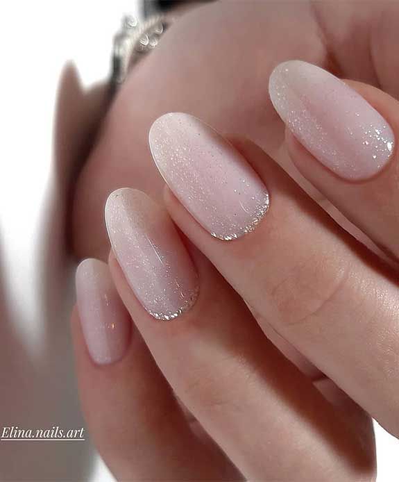 Elegant Pale Pink Gradient Nail Design with Subtle Sparkles and Oval Shape.