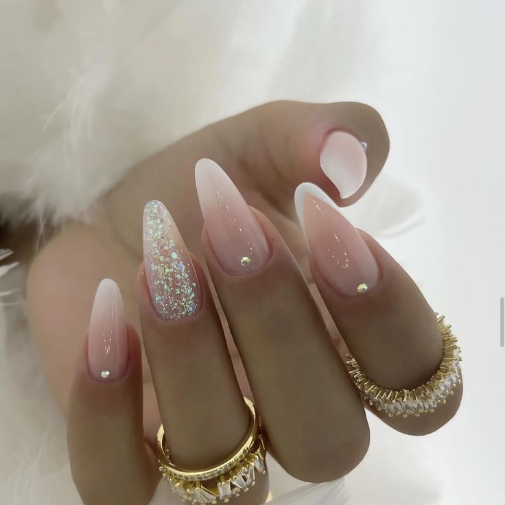 Elegant Ombre Nail Design with Soft Pink Gradient, Glitter Accents, and Subtle Gem Embellishments.