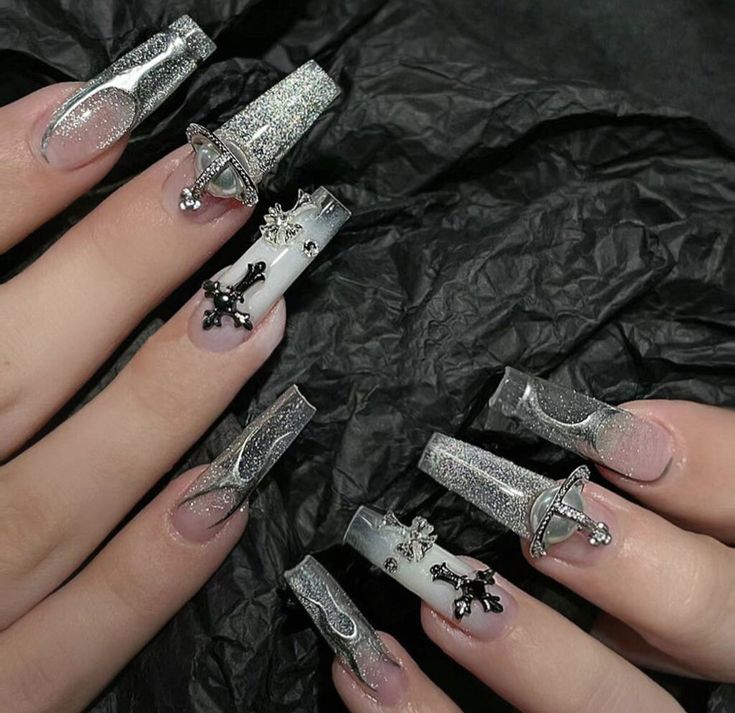 Elegant Glittering Nail Design with Elongated Shapes and Metallic Embellishments.