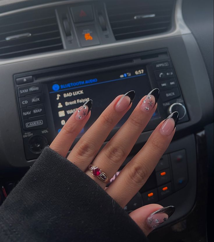 Chic Nail Design: Soft Pink Base with Bold Black Tips and Sparkling Embellishments