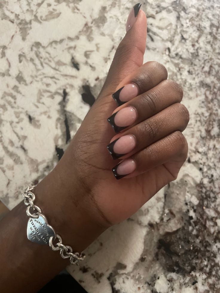 Sophisticated Black French Tip Manicure with Nude Base, Accented by a Stylish Silver Bracelet.