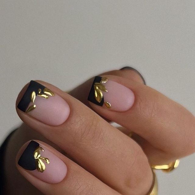 Sophisticated Nail Design: Soft Nude and Bold Black with Gold Leaf Accents.