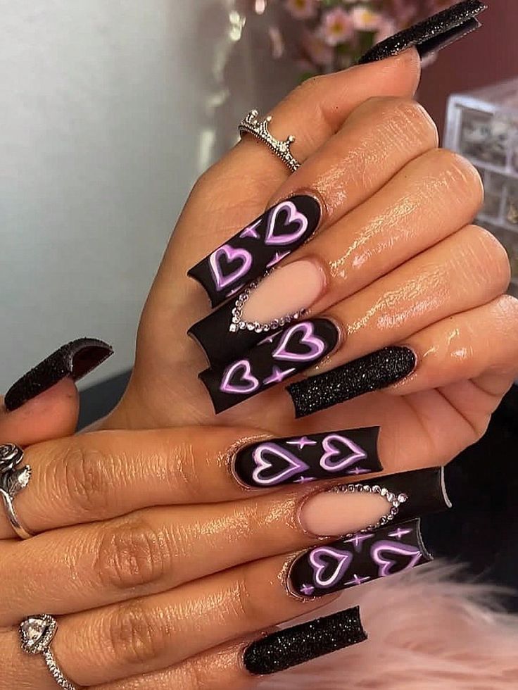 Chic Bold Nail Art: Matte Black and Glossy Pink Heart Motifs with Rhinestone Accents.