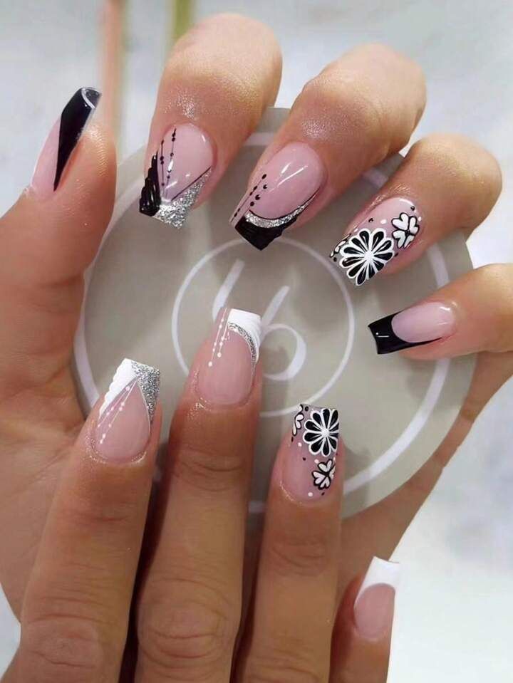 Sophisticated Nail Design: Soft Pink and Bold Black with Floral Patterns and Glittery Tips.