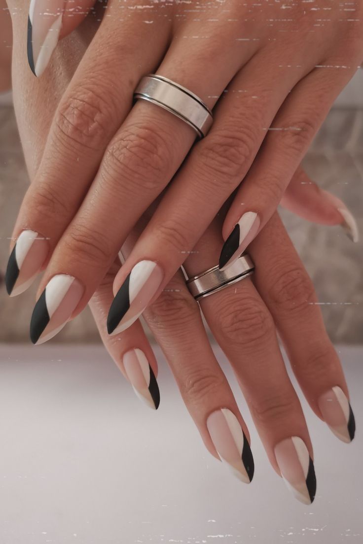 Chic Black and White Geometric Nail Design with Inverted Triangle Patterns and Stylish Silver Accessories.