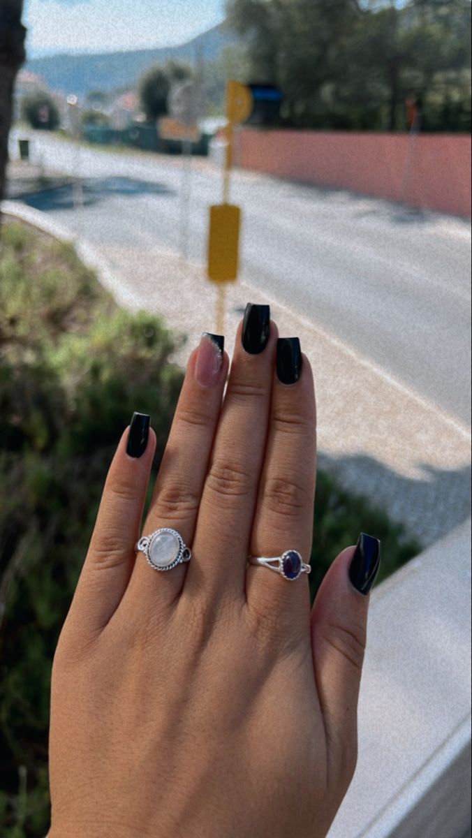 Sophisticated Elegance: Striking Black Nails and Chic Hand Pose with Delicate Accessories.