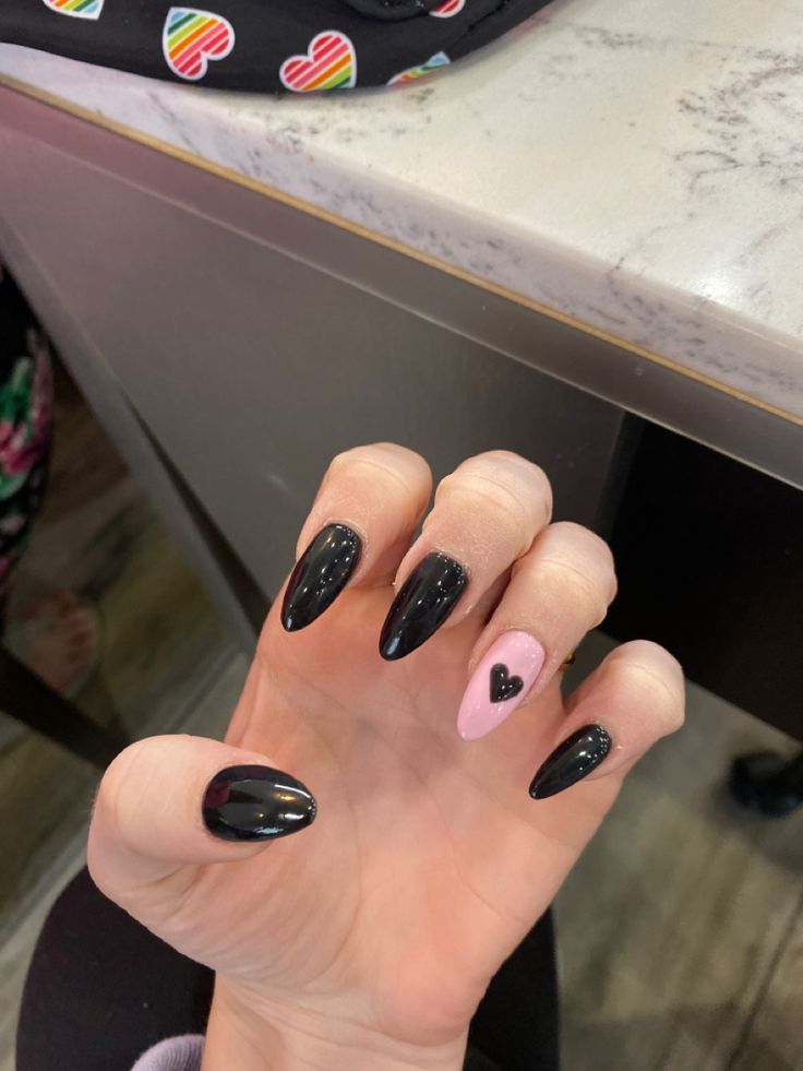 Chic Almond-Shaped Nails: Bold Black with a Playful Pink Heart Accent.