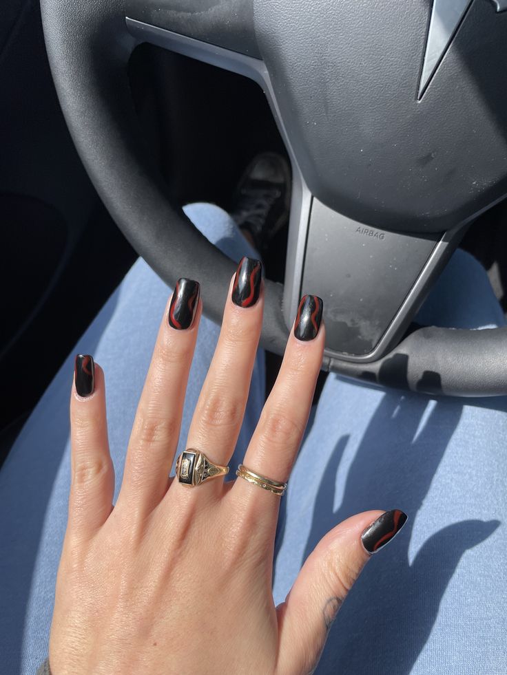 Bold Black Nail Design with Dramatic Red Swirls for a Striking Statement.