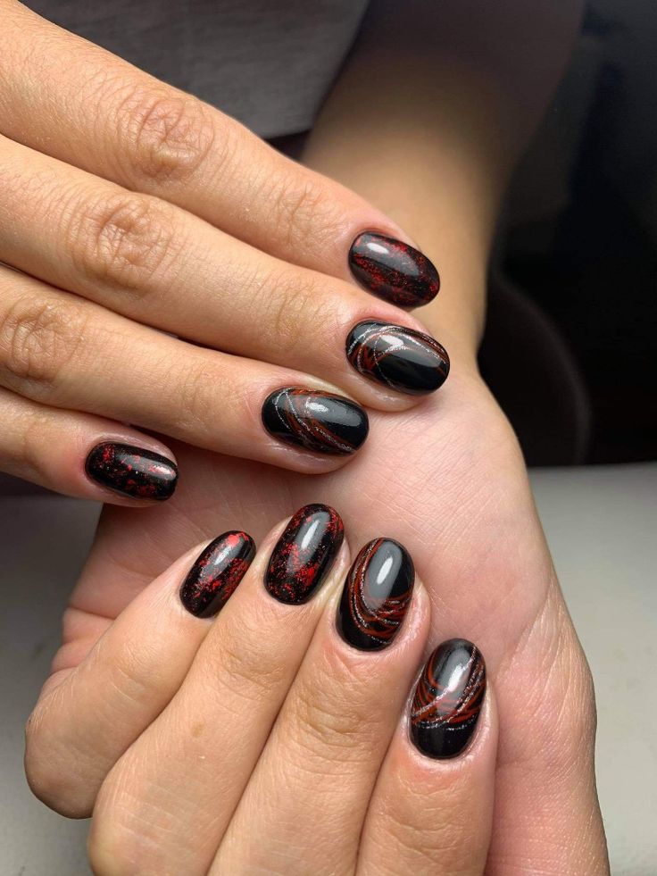 Bold Black and Red Nail Design with Glitter Accents and Artistic Swirls.