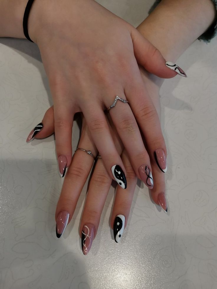 Elegant Nude and Black Geometric Nail Design with Sophisticated Accessories.