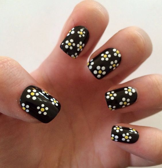 Chic Floral Nail Design: Elegant Black Base with Playful White and Yellow Accents.