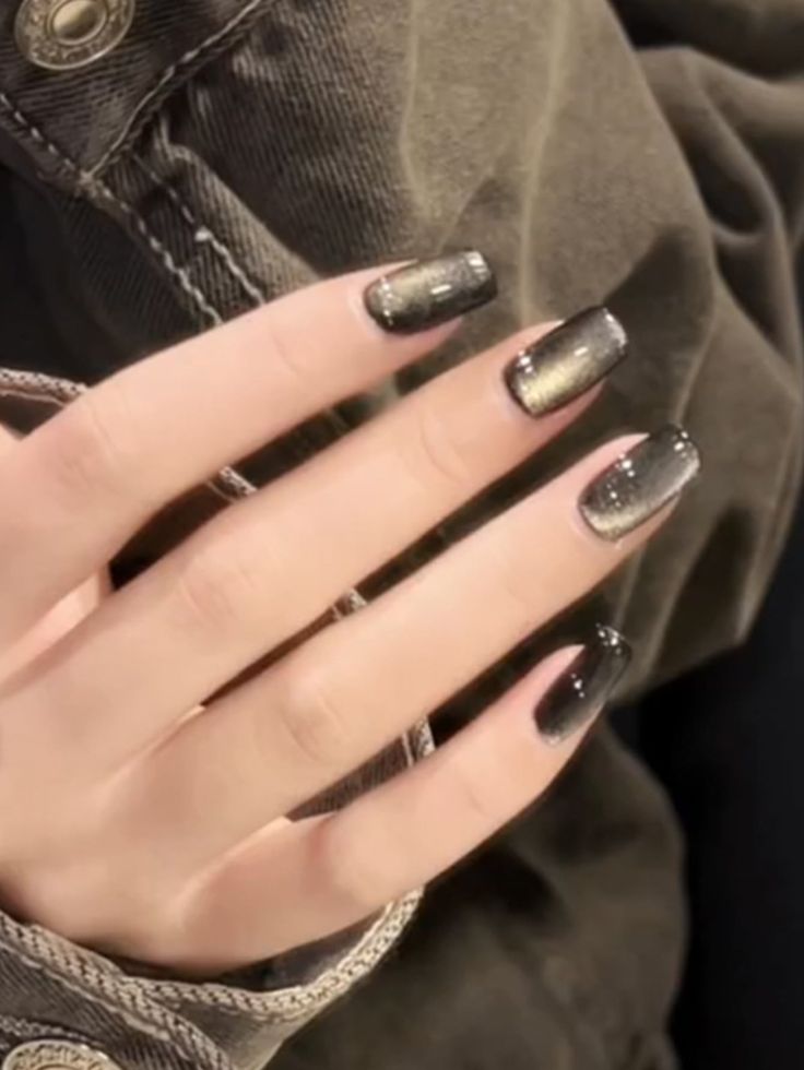 Sophisticated Chic Nail Design: Glossy Black to Shimmering Gold Gradient with Sparkle.