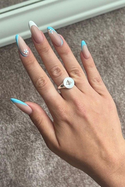 Elegant Almond-Shaped Nail Design: Nude and Pastel Colors with Floral Accents and Vibrant Blue Tips.