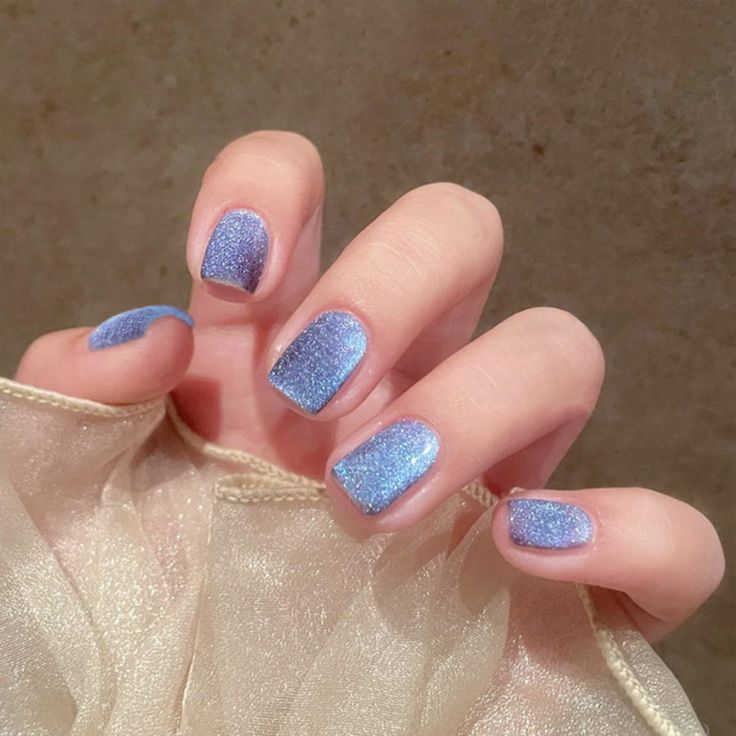 Captivating Glittering Blue Nail Design: A Shimmering Blend of Light and Dark Shades for an Elegant Finish.