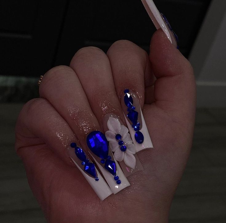 Glamorous White and Sparkling Blue Nail Design with Rhinestones and Floral Accents.