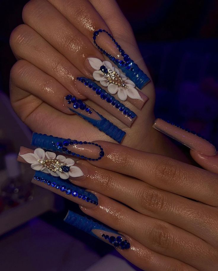 Vibrant Blue Accent Nail Design with Elongated Tips and Floral Embellishments