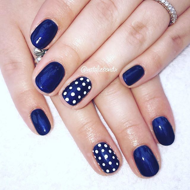 Sophisticated Navy Nail Design with Playful White Polka Dots and Mixed Finishes.