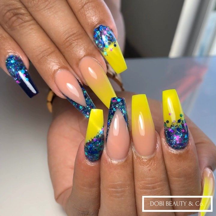 Vibrant Summer Manicure: Bold Yellow and Deep Blue with Glitter Accents on Nude Bases.