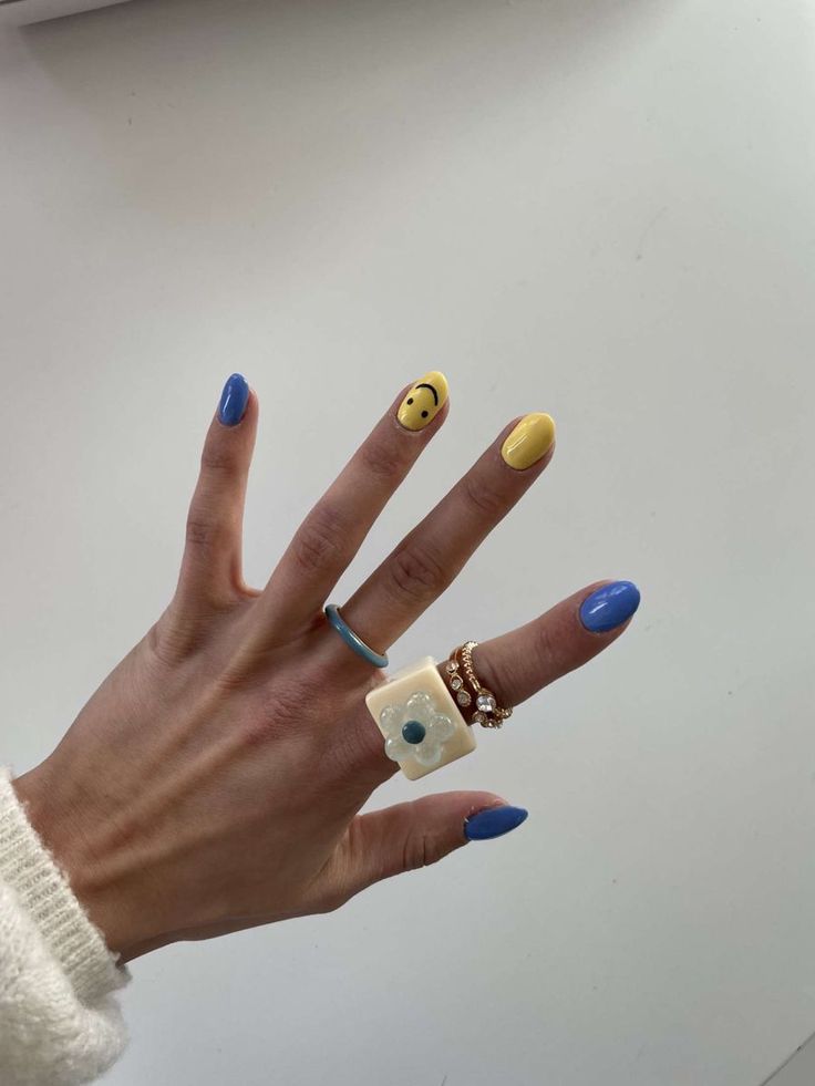 Playful Colorful Manicure with Whimsical Smiley Accent and Stylish Rings.