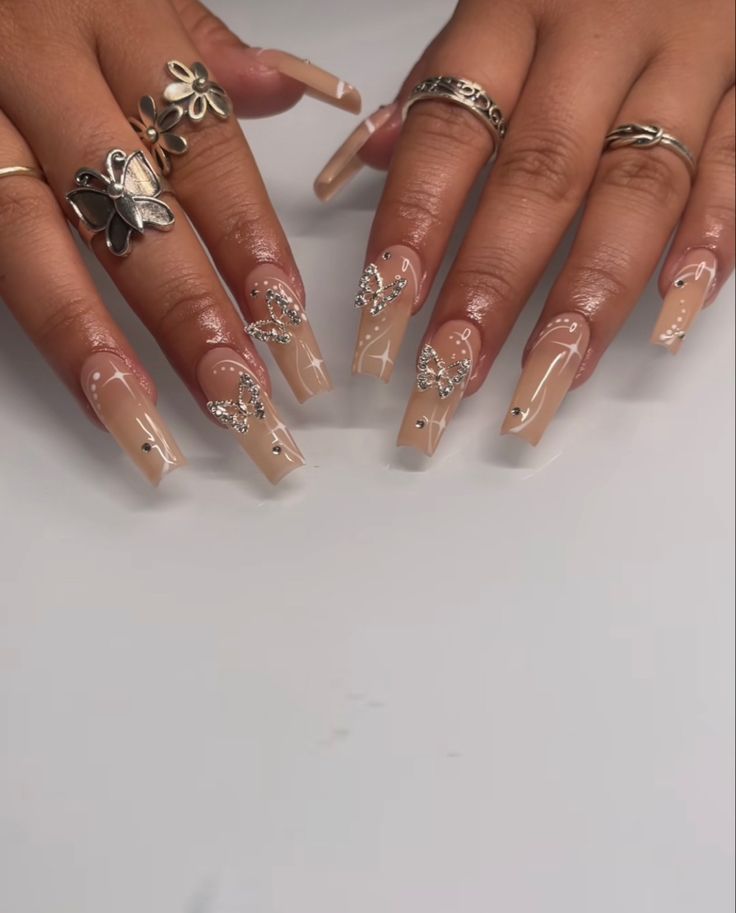 Sophisticated Nude Nail Design with Delicate Butterfly Accents and Sparkling Gems