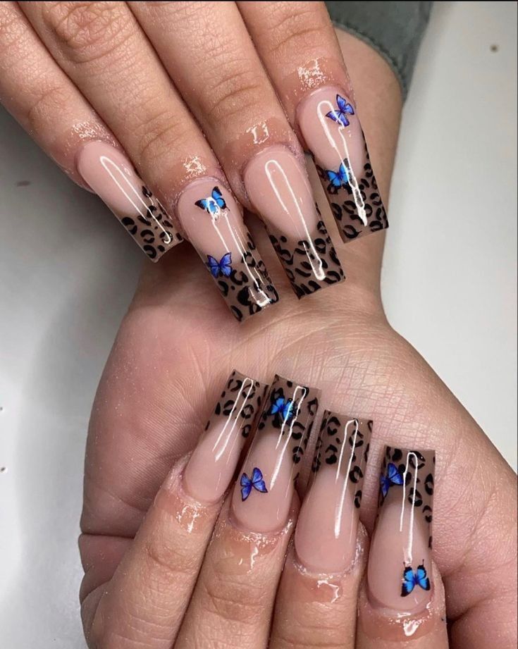 Trendy Nude and Animal Print Nail Design with Leopard Tips and Blue Butterfly Accents.