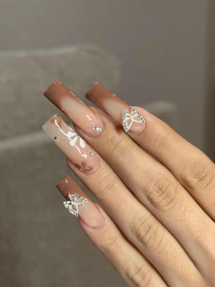 Elegant Nail Design: Chic Nude and Brown Blend with Whimsical Butterfly Accents.