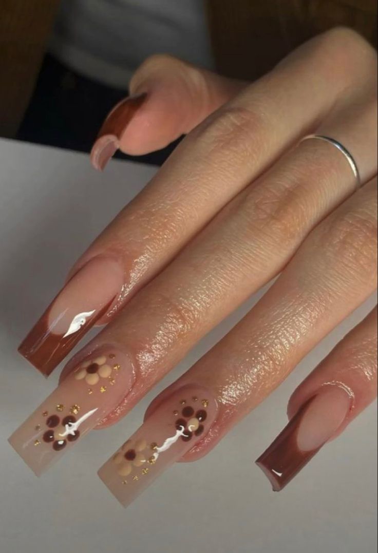 Chic and Sophisticated Nail Design with Rich Brown and Soft Nude Shades, Floral Accents, and Gold Embellishments.