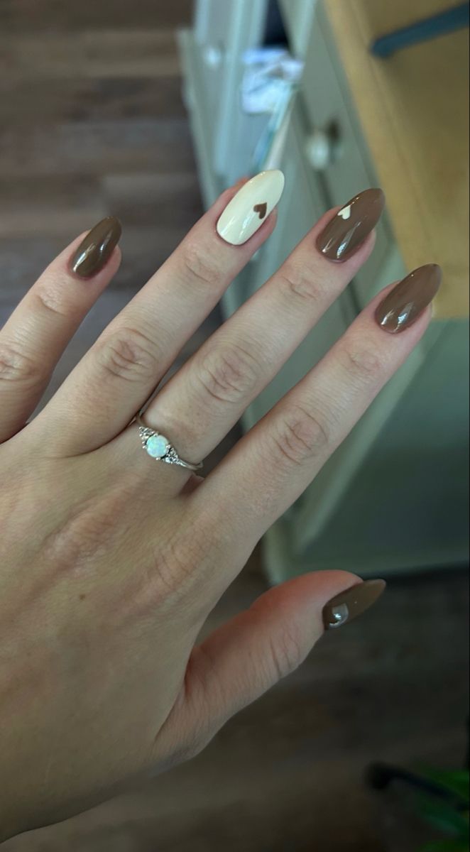 Chic Brown and Cream Nail Design with Playful Heart Accent.