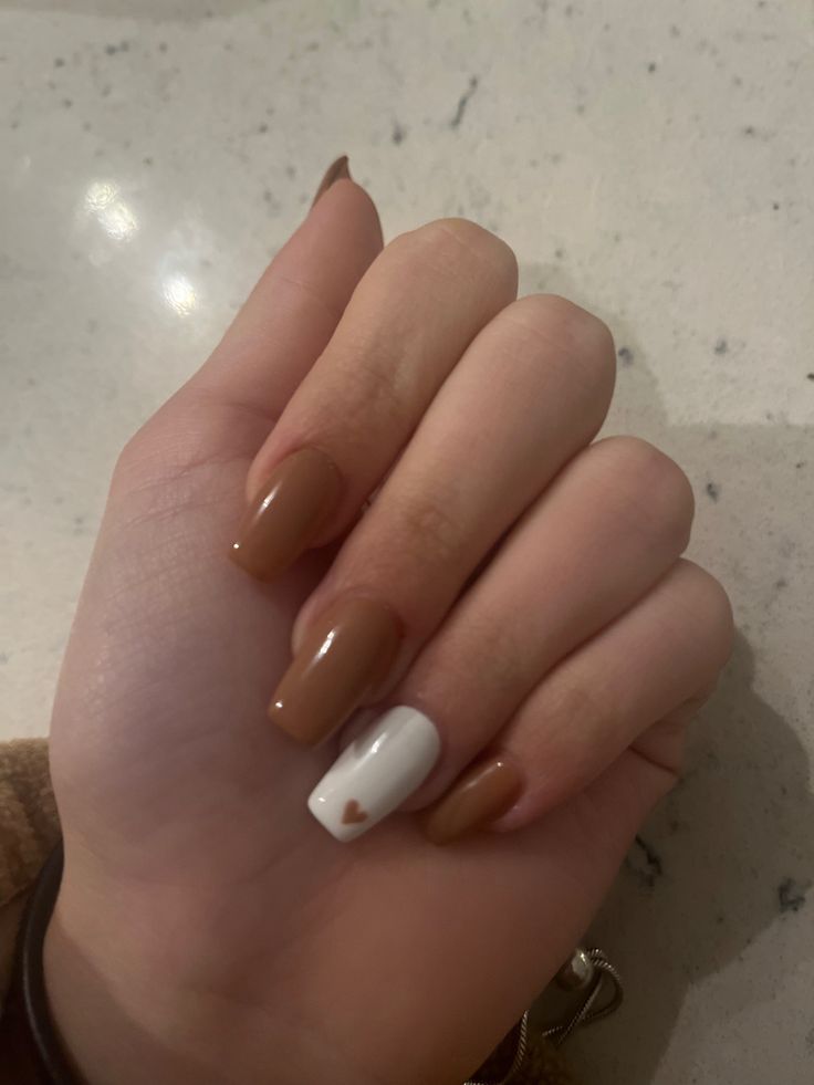 Chic Nail Design: Warm Brown Base with Glossy Finish and Playful White Heart Accent.