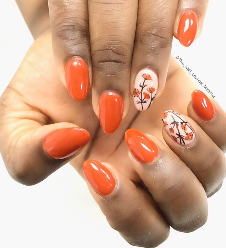 Bold Orange Nails with Elegant Floral Accent for a Striking Statement Look.