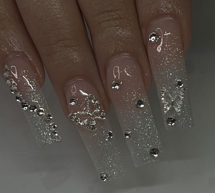 Stunning Gradient Sparkle Long Nails with Rhinestones and Butterfly Designs for Special Occasions.