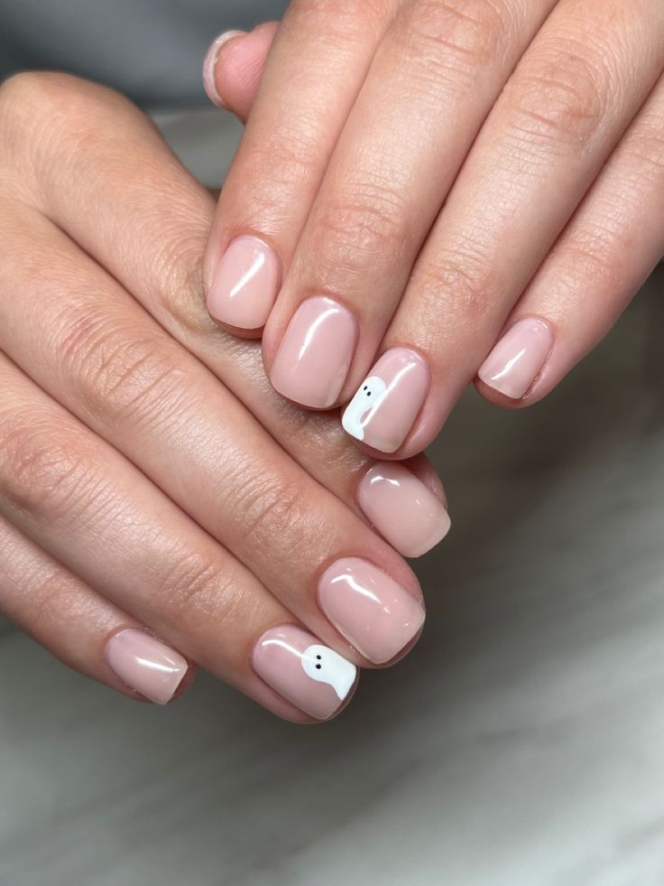 Chic Nude Nail Design with Playful Ghost Face Accents for a Unique Touch.