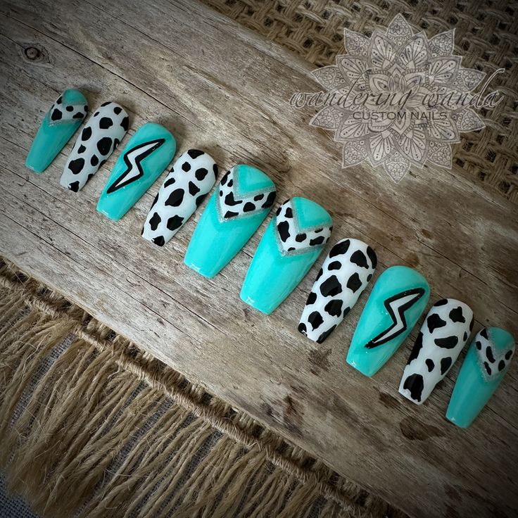 Edgy Turquoise and Black-White Nail Design with Bold Lightning and Playful Cow Prints.