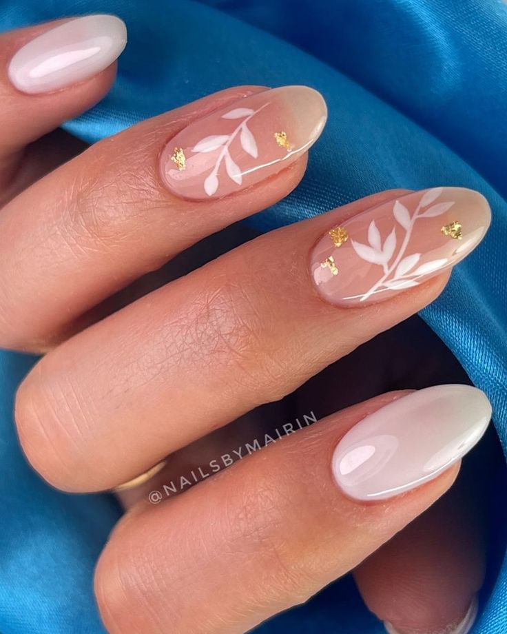 Elegant Nude Nail Design with White Leaf Patterns and Gold Foil Accents.