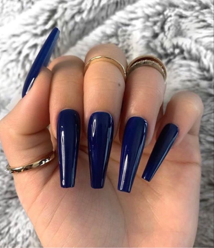 Elegant Stiletto Nail Design in Glossy Navy Blue with Delicate Rings.