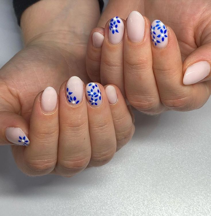 Elegant Nude Nail Design Accentuated with Vibrant Blue Floral Patterns.