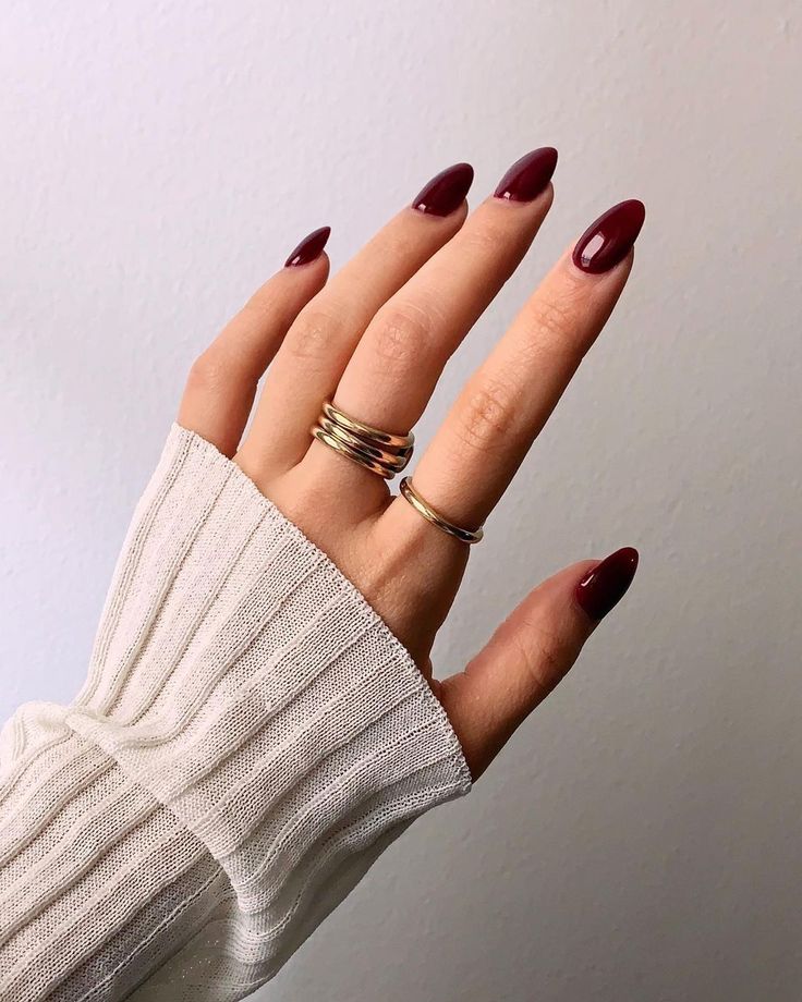 Chic Almond-Shaped Burgundy Nails Enhanced by Elegant Accessories and Cozy Textiles.