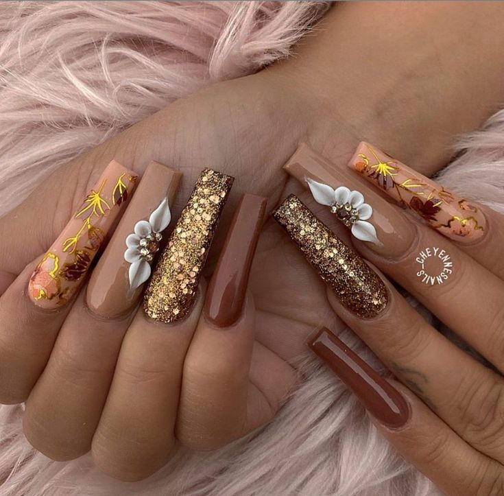 Sophisticated Nude and Warm Brown Nail Design with Floral Motifs and Glitter Accents