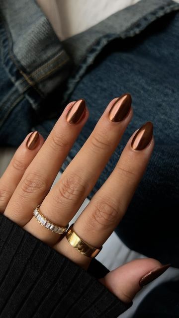 Elegant Metallic Brown Almond Nails with Chic Gold and Silver Accessories.