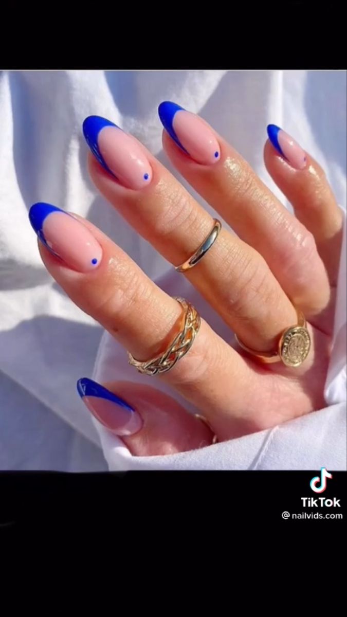 Elegant Blue French Tip Nail Design with Sophisticated Nude Base and Adorned Rings.