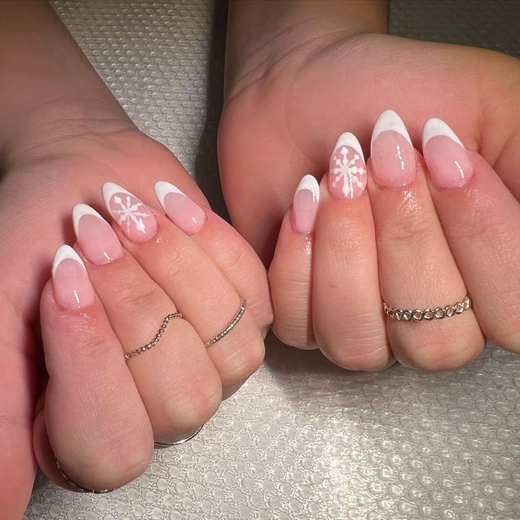 Elegant Winter French Manicure with Snowflake Accents on Soft Pink Base.