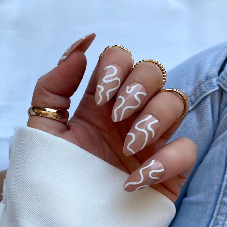 Chic Almond-Shaped Nails: Nude Base with Wavy White Lines for Elegance and Trendiness.