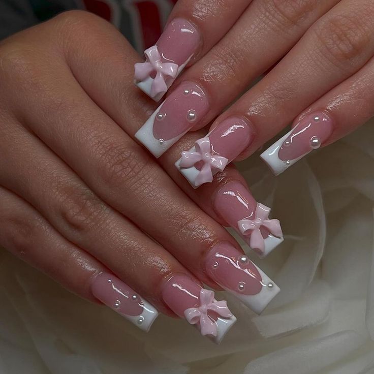 Elegant Pink and White Nail Design with Playful Bows and Pearl Accents for Special Occasions.