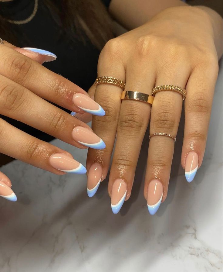 Chic French Manicure: Soft Nude Base with Delicate Baby Blue Tips and Dainty Rings.