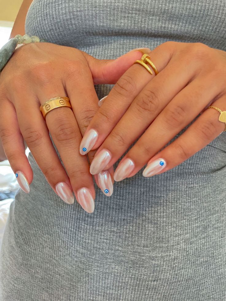 Chic Pearlescent Almond-Shaped Nails with Delicate Blue Rhinestone Accents and Stylish Ring Enhancements.